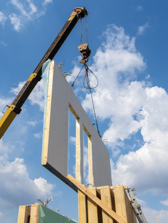 a crane lifts part of a home under construction